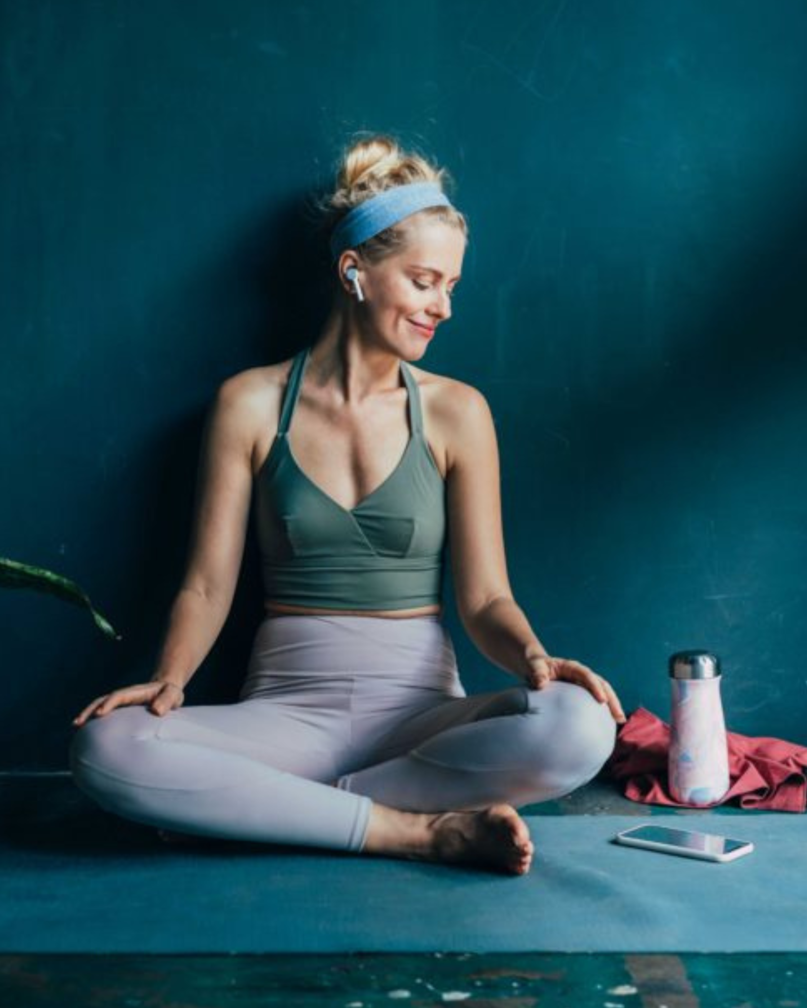 Frau in Yoga Bekleidung sitzt auf Yoga Matte
