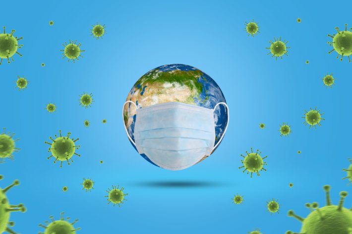 Im Zentrum steht eine Weltkugel mit einem Mundschutz umgeben von grünen Viren.